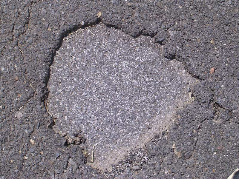Pothole caused by delamination due to inadequate or missing tack coat.